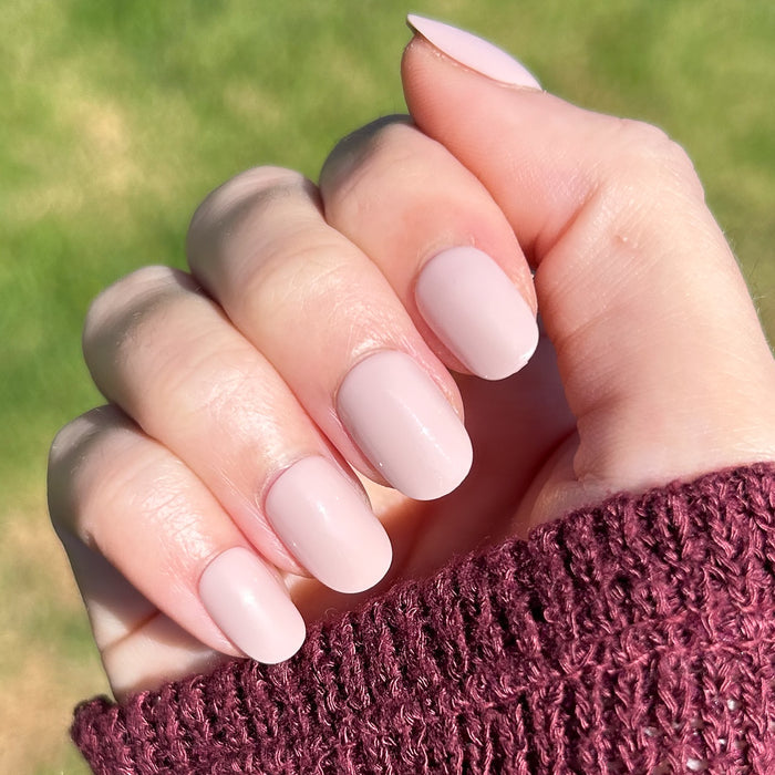 Kitten | Extra Short | Round - Tab Press-On showing soft neutral greige press-on nails on hand outdoors in natural light