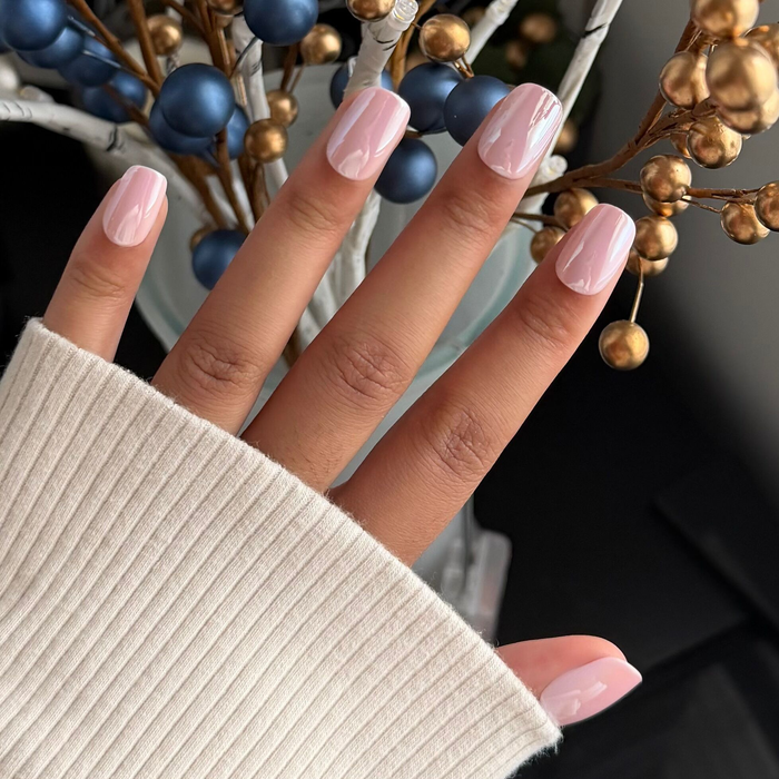 Hand with Pink Sands Chrome - Tab Press On | Short | Squoval false nails in cool pastel pink with shimmering chrome finish near decorative elements