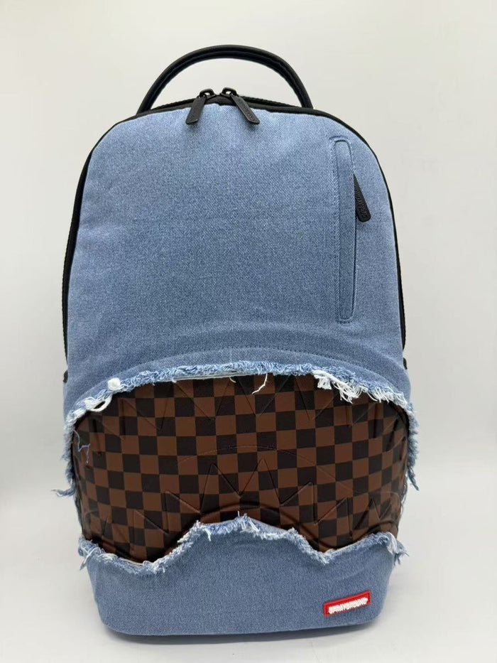 A stylish Sprayground Denim Shark Bite DLXSV Backpack made of 100% cotton denim twill, measuring 18 inches by 115 inches by 65 inches