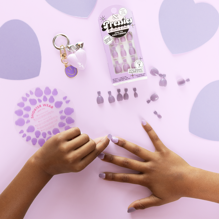 You're Invited - Pressies | Extra Short Short | Round showing hand with pastel purple press on manicure nails and nail size guide on lavender background