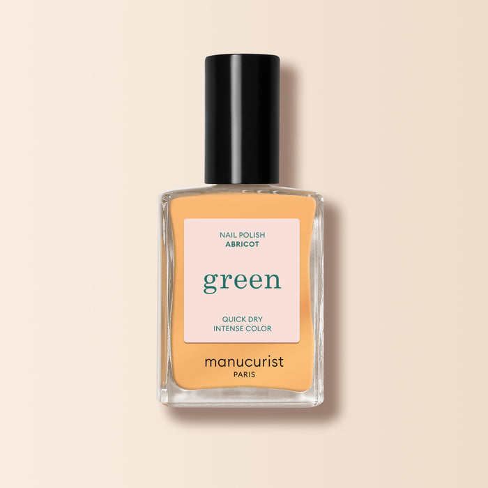 A bottle of Manucurist Abricot nail polish in a light apricot shade, featuring a black cap and set against a beige background.