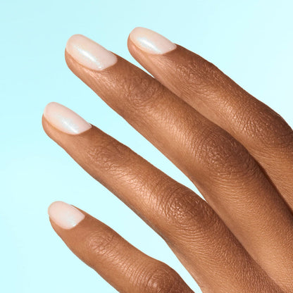 A close-up of a hand with medium brown skin and neatly manicured nails painted with Manucurist’s Active™ Plump Aqua Glazed—a soft, shimmery pale pink collagen nail polish—set against a light blue background.
