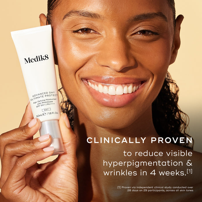 Close-up of a smiling woman with a radiant complexion holding a tube of Advanced Day Ultimate Protect. Text states: "CLINICALLY PROVEN to reduce visible hyperpigmentation & wrinkles in 4 weeks."