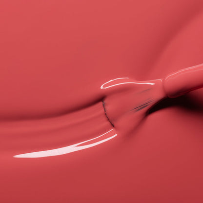 A close-up of a brush spreading Manucurist’s Bois de Rose nail polish, creating a smooth, glossy streak of rosewood pink across the surface.