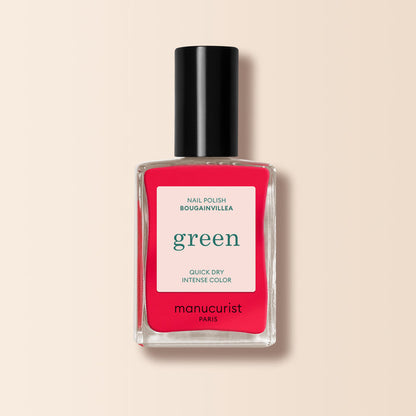 A bottle of Manucurist Bougainvillea—a bright reddish pink nail polish with a black cap and white label reading "green, quick dry intense color, and nail polish.