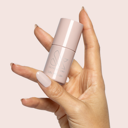 Hand holding a bottle of CDJ - Gel nail polish with neutral creamy shade on light beige background