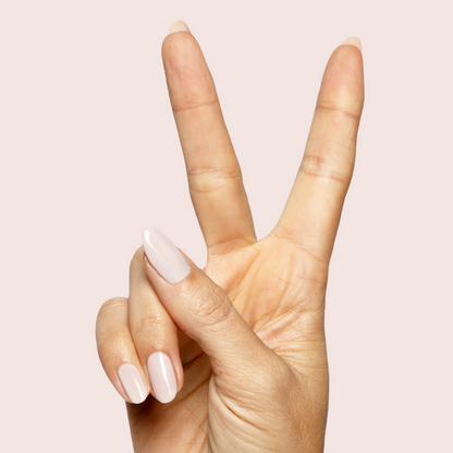 Hand showing long nails painted with CDJ - Gel creamy neutral gel polish on light beige background