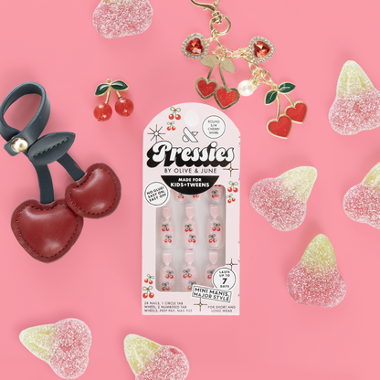 Cherry Whirl - Pressies | Short Medium | Round showing cherry-themed press on nails in packaging on pink background with cherry accessories