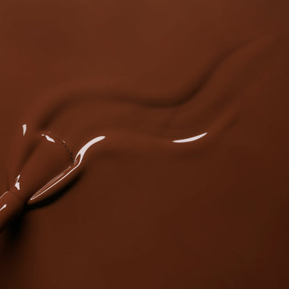 Close-up of smooth, melted chocolate in a warm brown hue being swirled, forming glossy waves that mirror the rich Chestnut shade of Manucurist's Green™ nail polish.