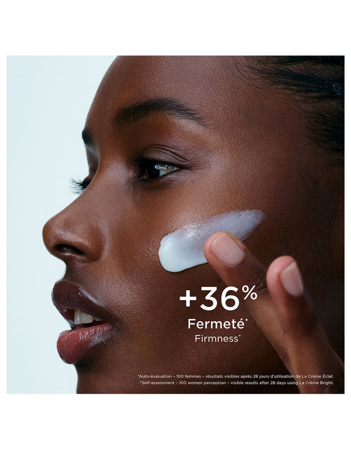 Clarins Precious La Crème Bright 50ml jar of luxurious skincare cream with a gold lid, displayed on a reflective surface.
