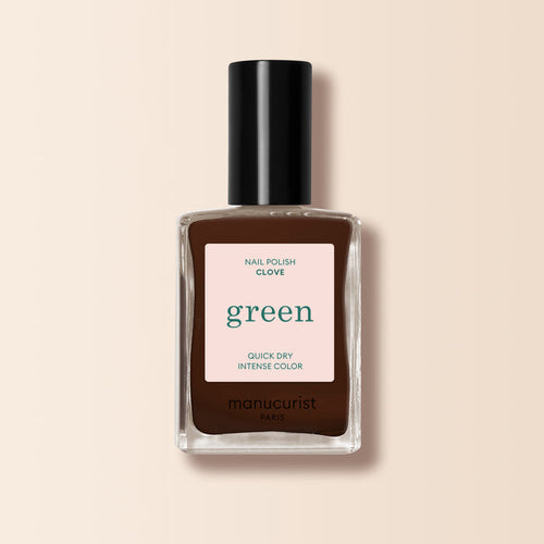 A bottle of Manucurist Clove nail polish, a chocolate brown shade from the Green™ range, features a black cap and a label reading "green, quick dry intense color" on a light beige background.