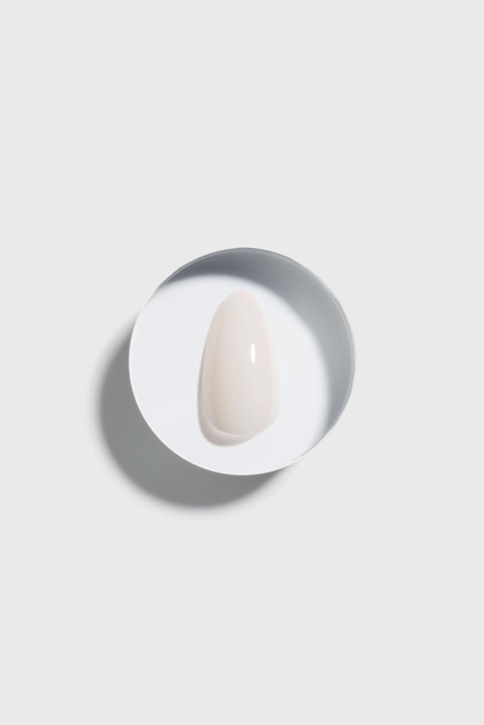 Coconut Milk  press-on nail on a white ceramic plate on a light gray background