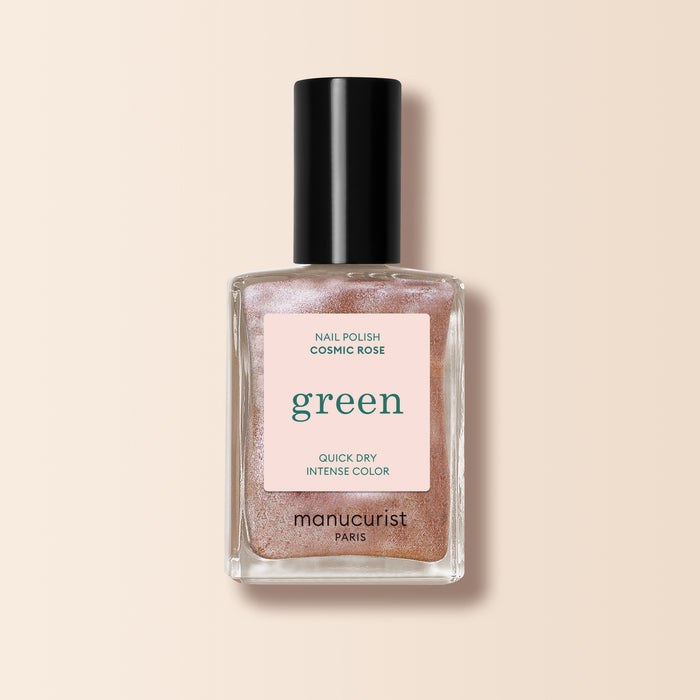 A bottle of Manucurist nail polish in the shade Cosmic Rose, featuring shimmery, iridescent pink color with a black cap and a pink label that reads "green" and states Quick Dry Intense Color.