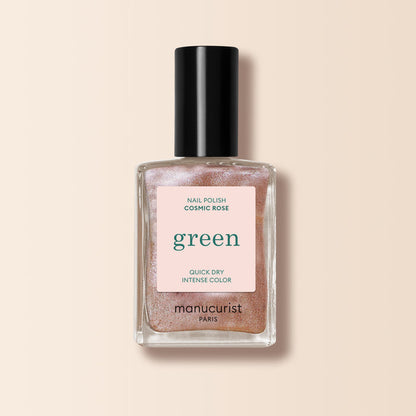 A bottle of Manucurist nail polish in the shade Cosmic Rose, featuring shimmery, iridescent pink color with a black cap and a pink label that reads "green" and states Quick Dry Intense Color.
