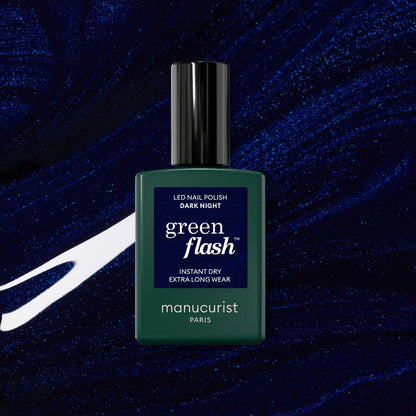 A bottle of Manucurist Dark Night gel polish is shown against a dark blue, shimmery abstract background with white streaks.