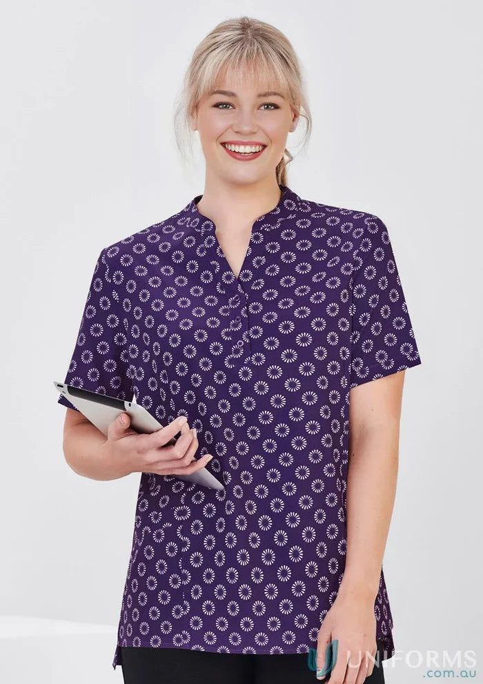 Woman in Bizcare women’s daisy print tunic with easy stretch daisy fabric holding tablet