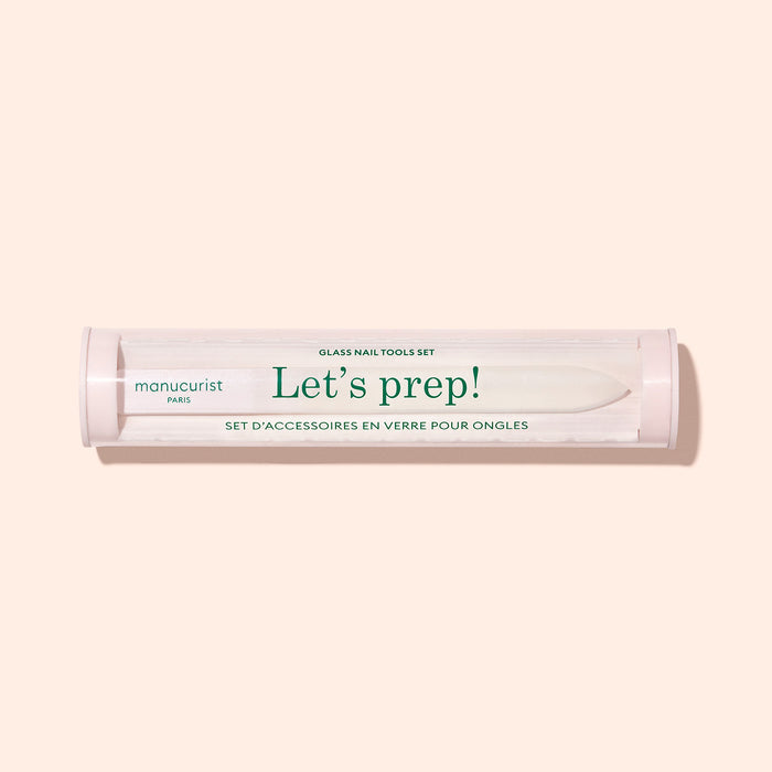 A cylindrical Lets prep! case holds the Manucurist-us Glass nail accessory trio, including a glass cuticle pusher and nail file, shown on a light beige background.
