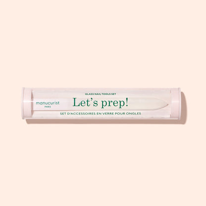 A cylindrical Lets prep! case holds the Manucurist-us Glass nail accessory trio, including a glass cuticle pusher and nail file, shown on a light beige background.