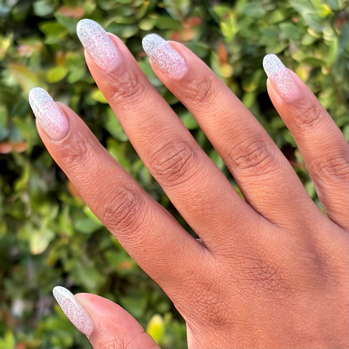 Glitter Department Gel on almond-shaped nails with a gradient of holographic silver for a festive mani by Olive and June