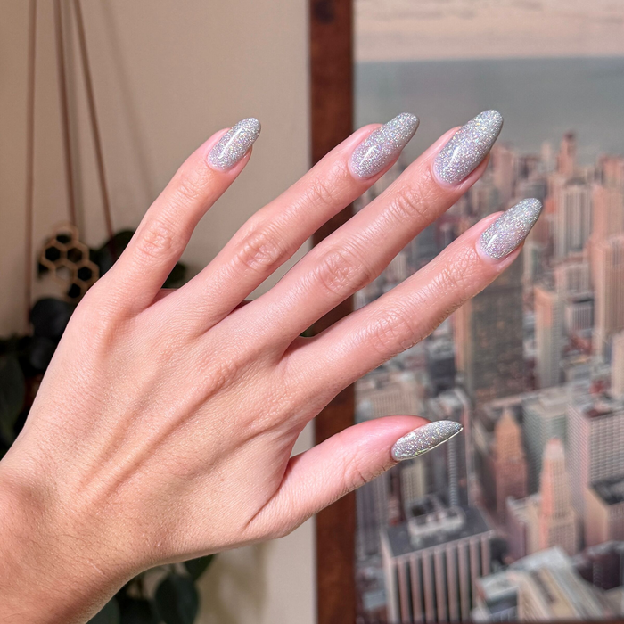 Glitter Department Gel on long almond-shaped nails with holographic silver sparkle for a festive manicure at home by Olive and June
