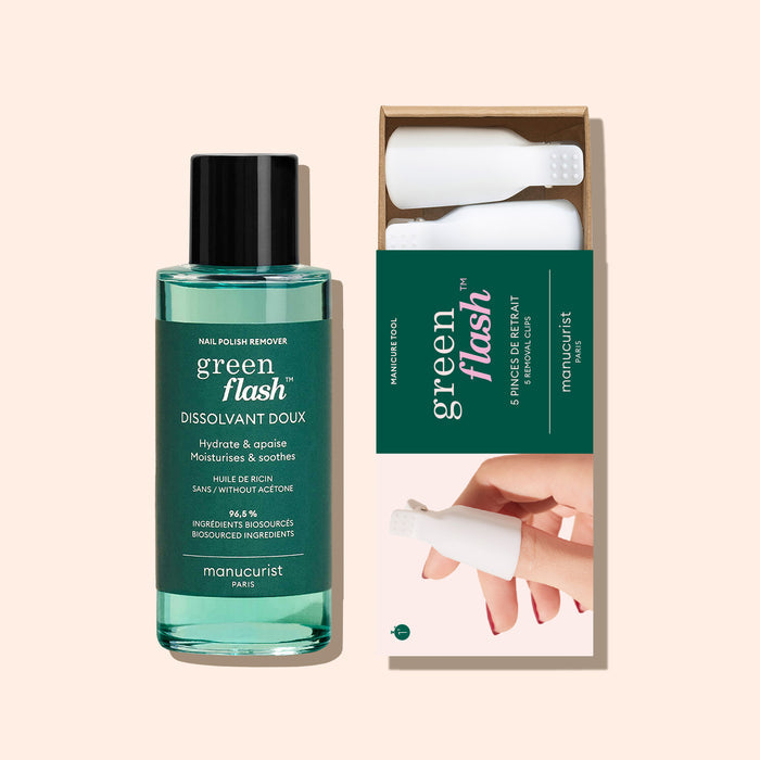 A bottle of Manucurist-us Green Flash™ Remover  Clips Duo stands beside an open box with five reusable fingertip clips, each featuring a white textured cap. The background is a soft beige color.