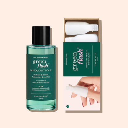 A bottle of Manucurist-us Green Flash™ Remover  Clips Duo stands beside an open box with five reusable fingertip clips, each featuring a white textured cap. The background is a soft beige color.