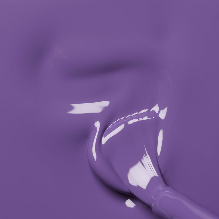 A close-up of a brush blending Manucurist's Iris, a smooth, glossy purple polish with blue undertones; light reflects off the wet surface and soft brushstrokes are visible.