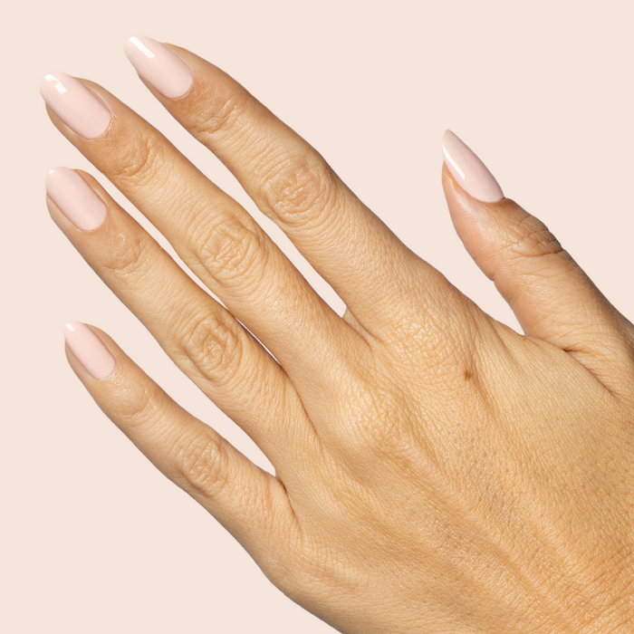 Hand with almond-shaped nails painted in KAG - Gel neutral peachy pink gel polish against soft beige background