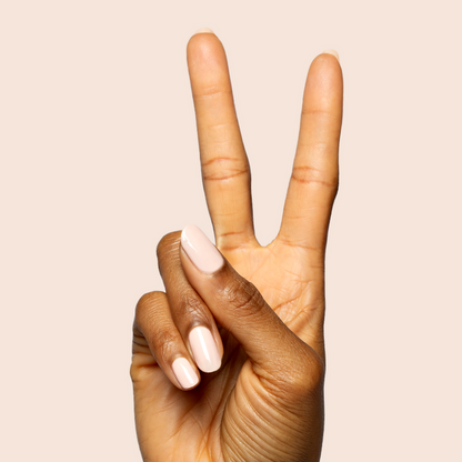 Hand with nails painted in KAG - Gel neutral peachy pink polish making a peace sign on soft beige background