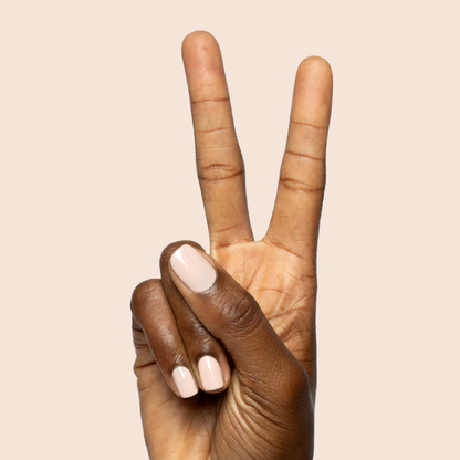 Hand showing peace sign with nails painted in KAG - Gel neutral peachy pink gel polish on light beige background