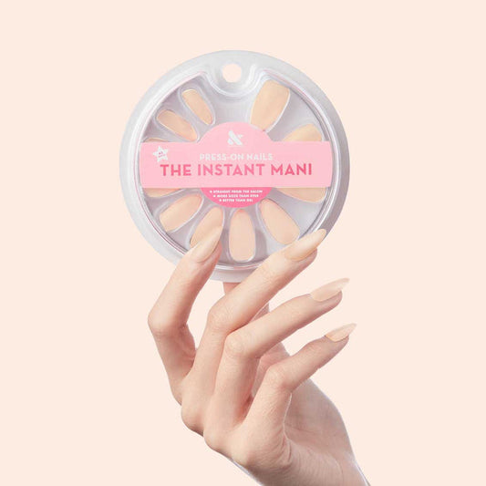 KAG - Press-On | Long | Almond showing hand holding long almond press-on nails in neutral peachy pink polish