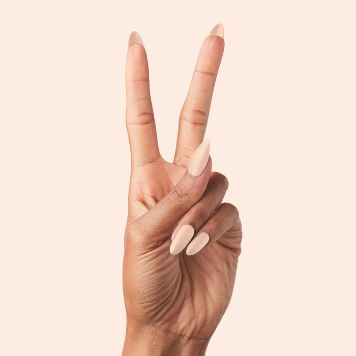 KAG - Press-On | Long | Almond showing hand with long almond press-on nails in neutral peachy pink polish on light background