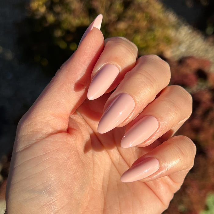 KAG - Press-On | Long | Almond showing hand with long almond press-on nails in soft neutral peachy pink mani polish outdoors