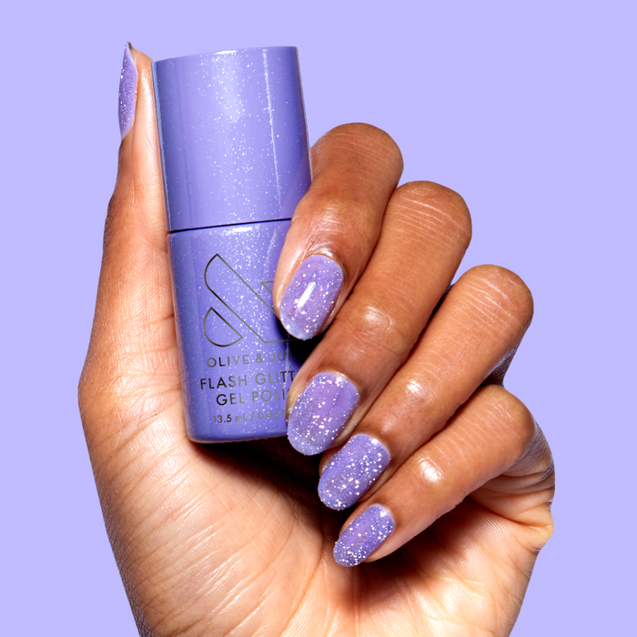 Hand holding Karaoke is a Good Time Gel bottle with purple flash glitter gel polish on natural nails for mani look