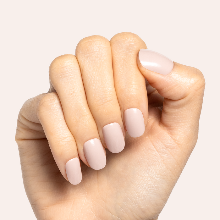 Kitten | Extra Short | Round - Tab Press-On showing soft neutral grey beige false nails on hand against pale background
