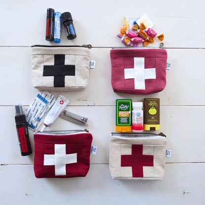 Four medium first aid kit pouches with cream cross patches, laid with small medical items