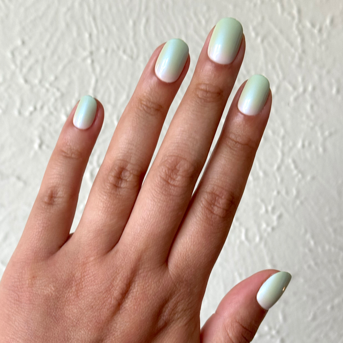 Hand displaying Minty Shimmer | Extra Short | Round - Tab Press-On nails in soft mint gradient with delicate shimmer finish