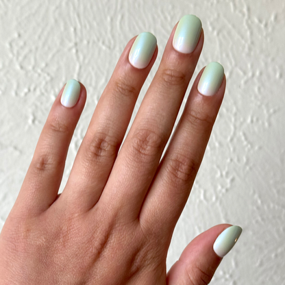 Hand displaying Minty Shimmer | Extra Short | Round - Tab Press-On nails in soft mint gradient with delicate shimmer finish
