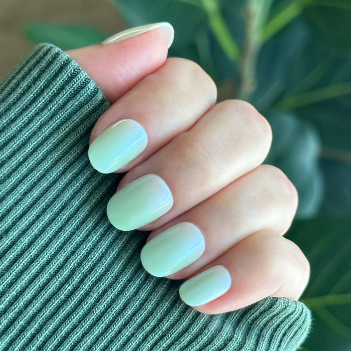 Hand with Minty Shimmer | Extra Short | Round - Tab Press-On nails in soft mint green gradient with subtle shimmer finish manicure