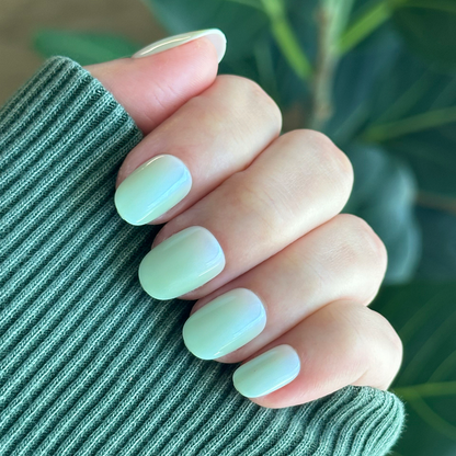 Hand with Minty Shimmer | Extra Short | Round - Tab Press-On nails in soft mint green gradient with subtle shimmer finish manicure