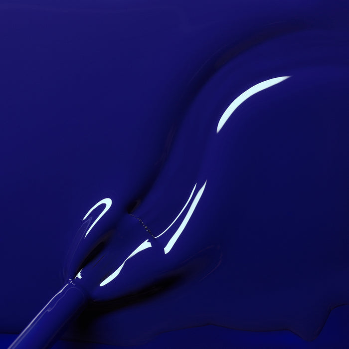 A close-up of a brush coated in Manucurist's Navy Blue polish, showcasing its smooth, glossy finish and reflective, curved surfaces.
