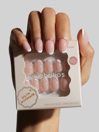 Hand holding a box of press-on nails with a neutral background
