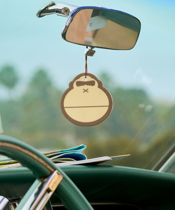 Original Scent Air Freshener by Sun Bum hanging from a vintage car rearview mirror inside a classic vehicle.