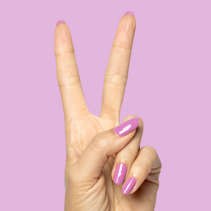 Hand showing peace sign with nails polished in bright floral purple Petal - Gel on soft lilac background