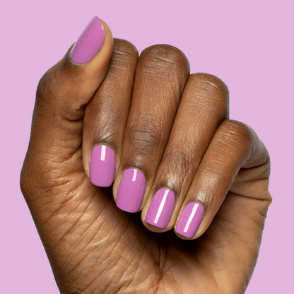 Hand with nails painted in bright floral purple pink shade using Petal - Gel polish on soft purple background