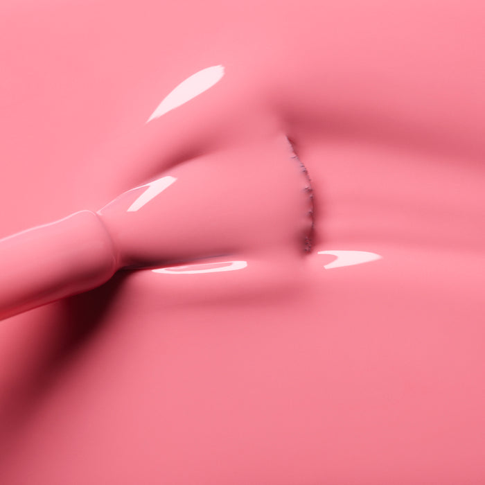 A close-up of a brush applying Manucurist Pink Paradise gel polish, creating smooth strokes and subtle texture on the glossy pink surface.
