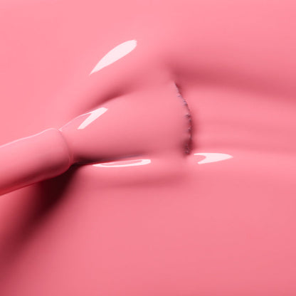 A close-up of a brush applying Manucurist Pink Paradise gel polish, creating smooth strokes and subtle texture on the glossy pink surface.
