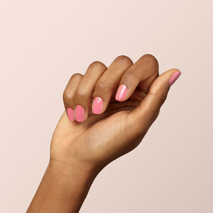 A hand with medium brown skin is displayed against a plain light background, nails neatly manicured and painted with Manucurist’s Pink Paradise, a glossy candy pink gel polish.