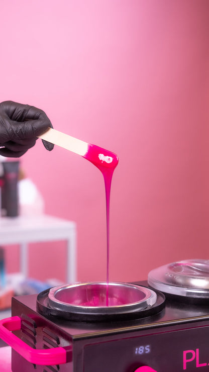 Person holding pink wax with a stick over a pink background