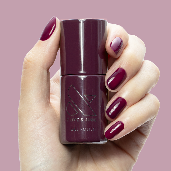 Plaza - Gel bottle held by hand with deep mulberry purple gel polish on nails for a luxe manicure by Olive and June